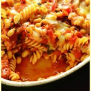 Top down view of bean pasta bake in oval casserole dish on oven tray.