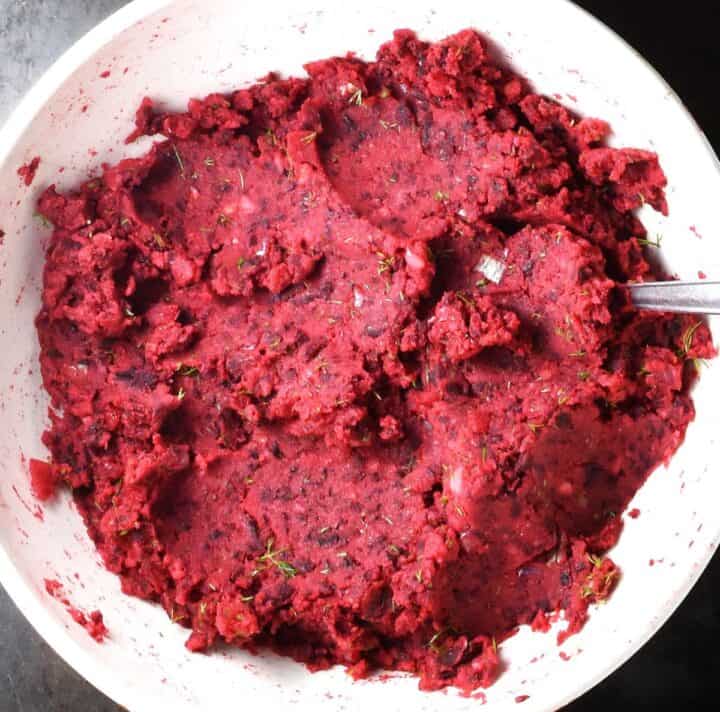 Top down view of creamy beet and potato cakes mixture in white bowl.