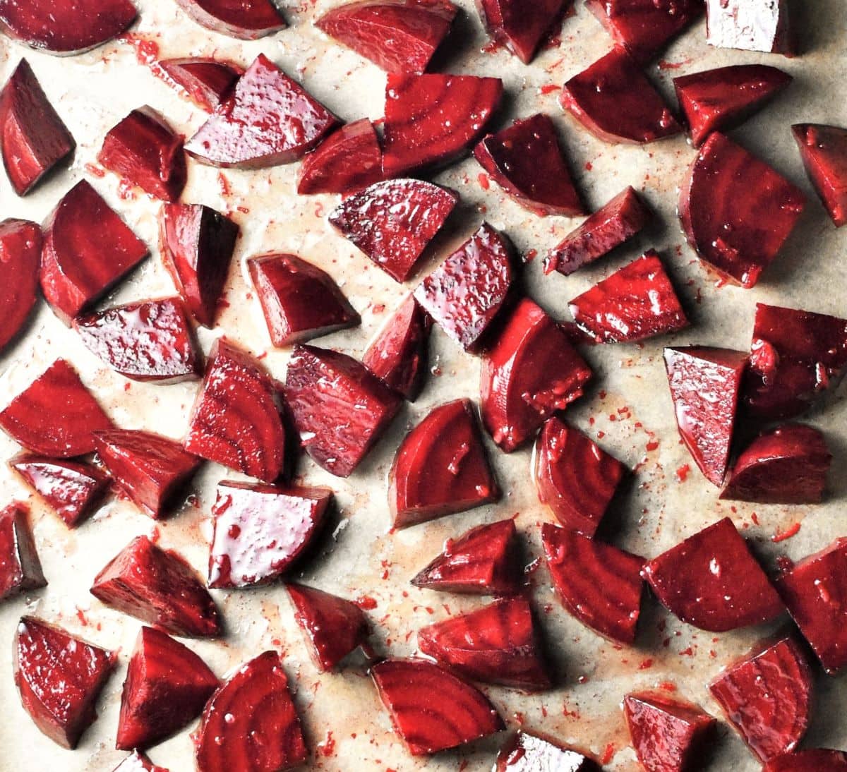 Small beetroot wedges coated in oil on top of parchment.