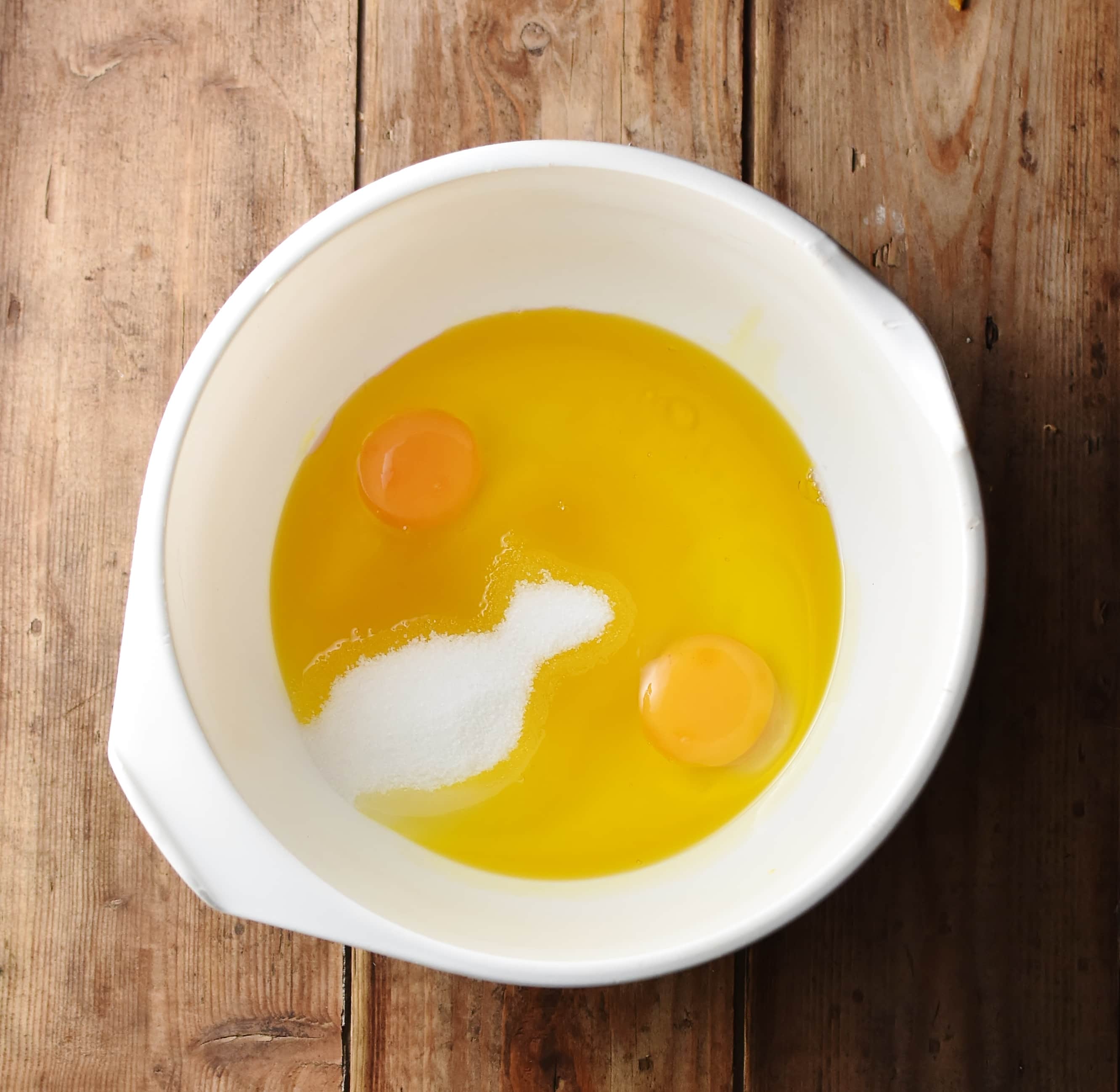 Sugar, oil and 2 eggs in large white bowl.