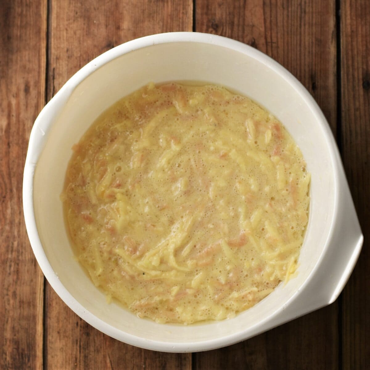 Batter with grated apple in large white bowl.