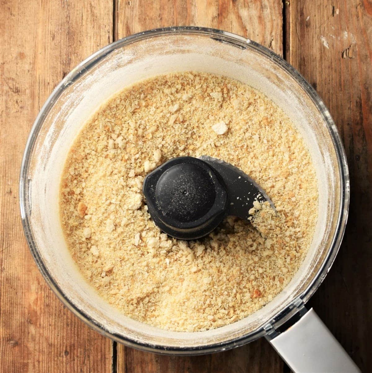 Top down view of fine breadcrumbs inside food processor.