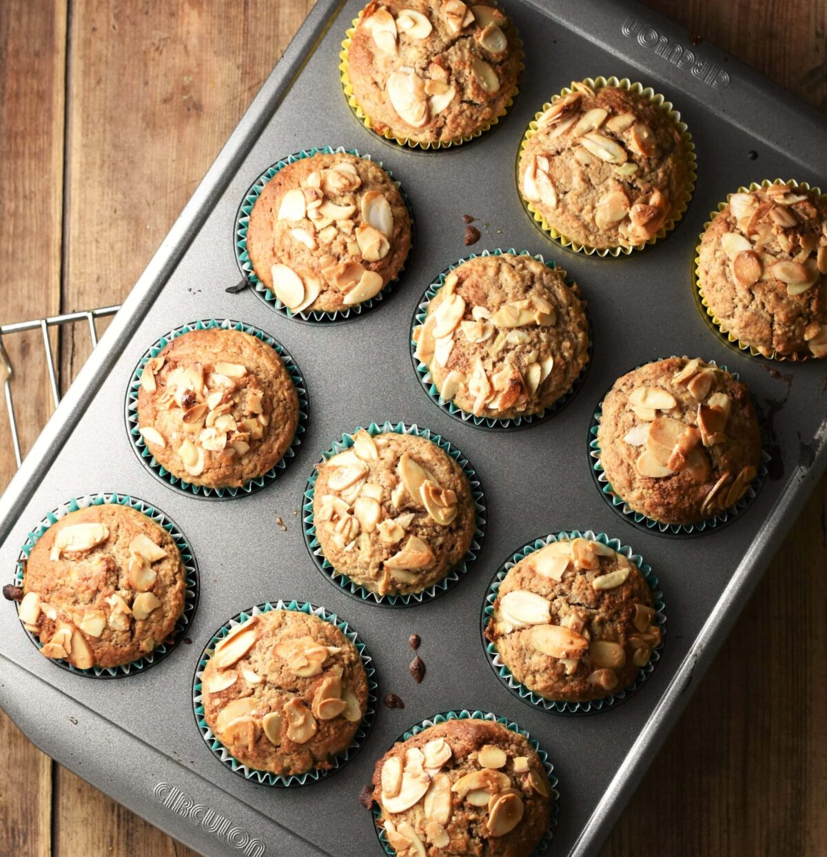 12 apple muffins with almond flakes on top in muffin pan.