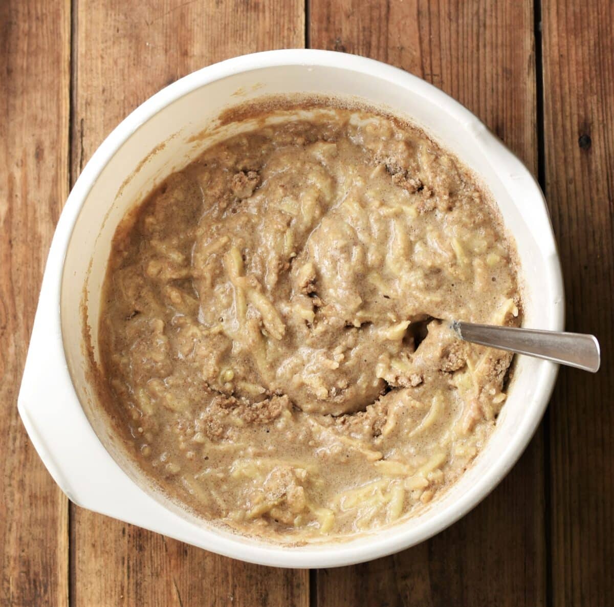 Lumpy batter in large white bowl with spoon.