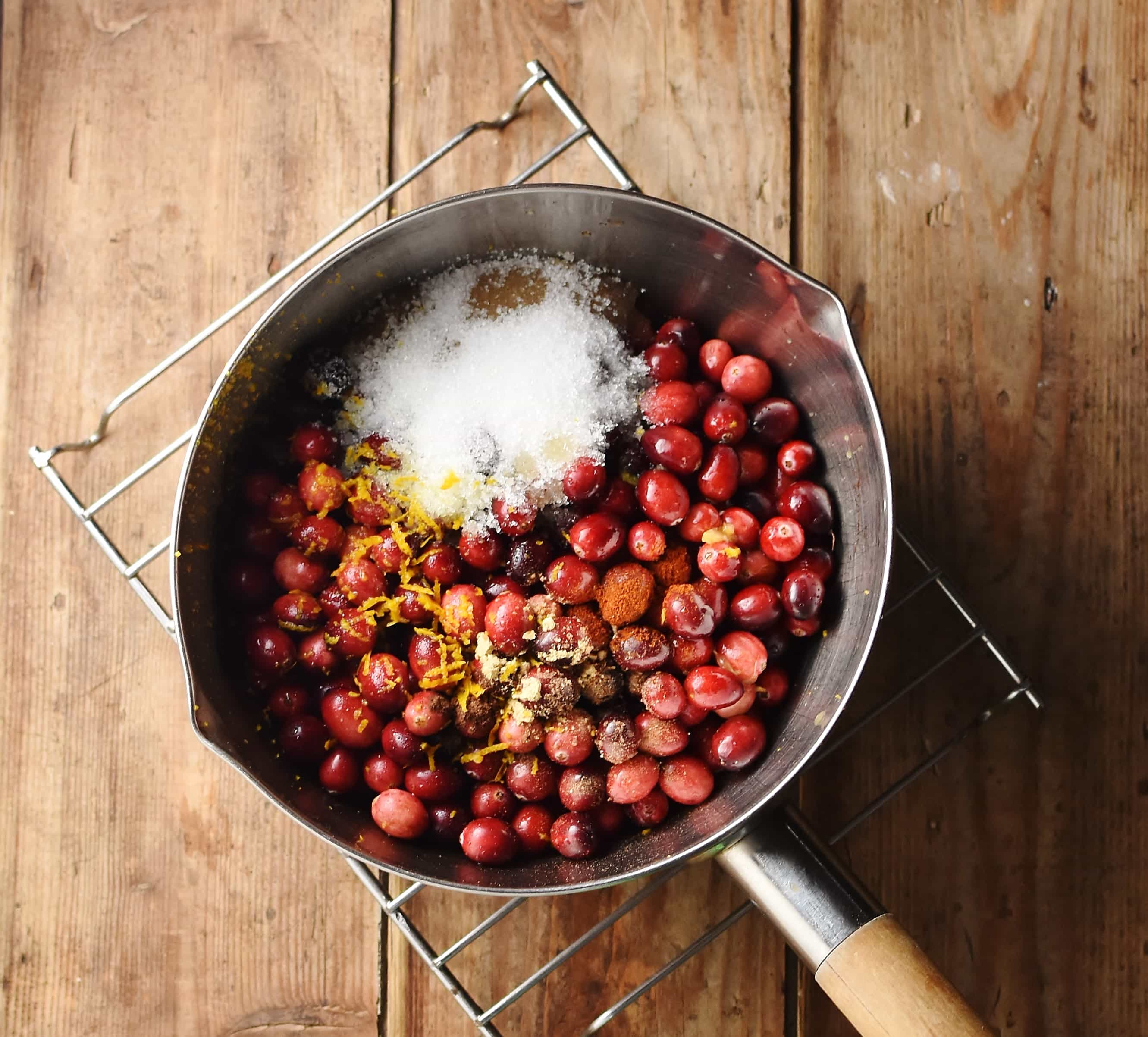 Cranberries with sugar and spice in saucepan.