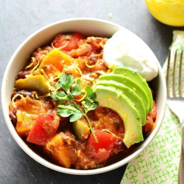 Chunky butternut squash chilli with vegetables in white bowl.