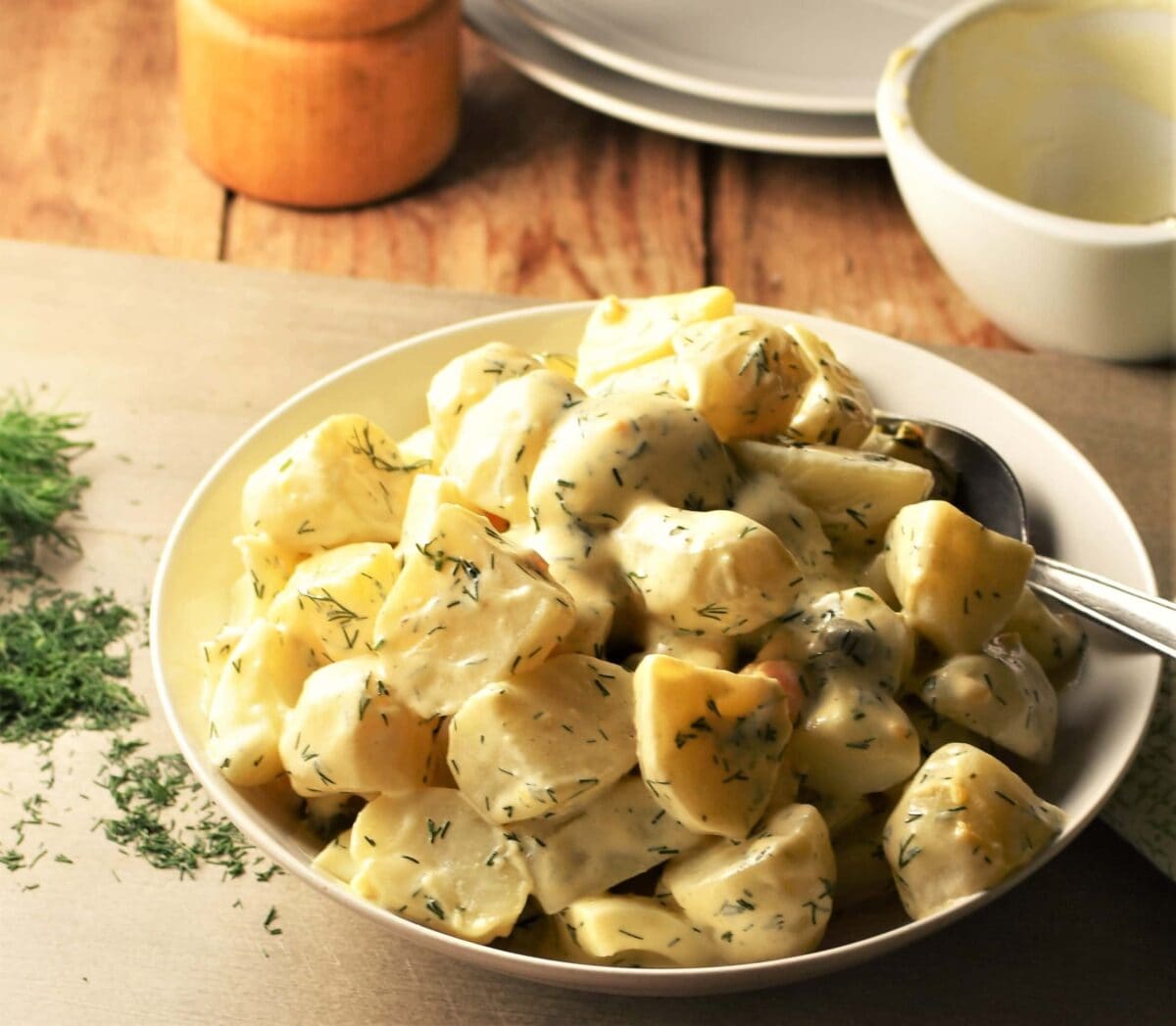 Side view of dill and potato salad in white bowl.
