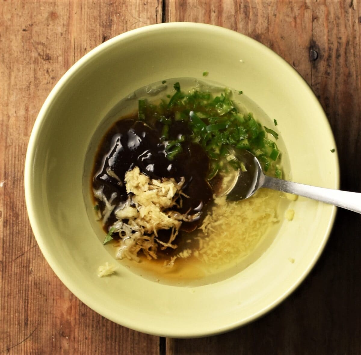 Hoisin dressing ingredients in yellow bowl with spoon.