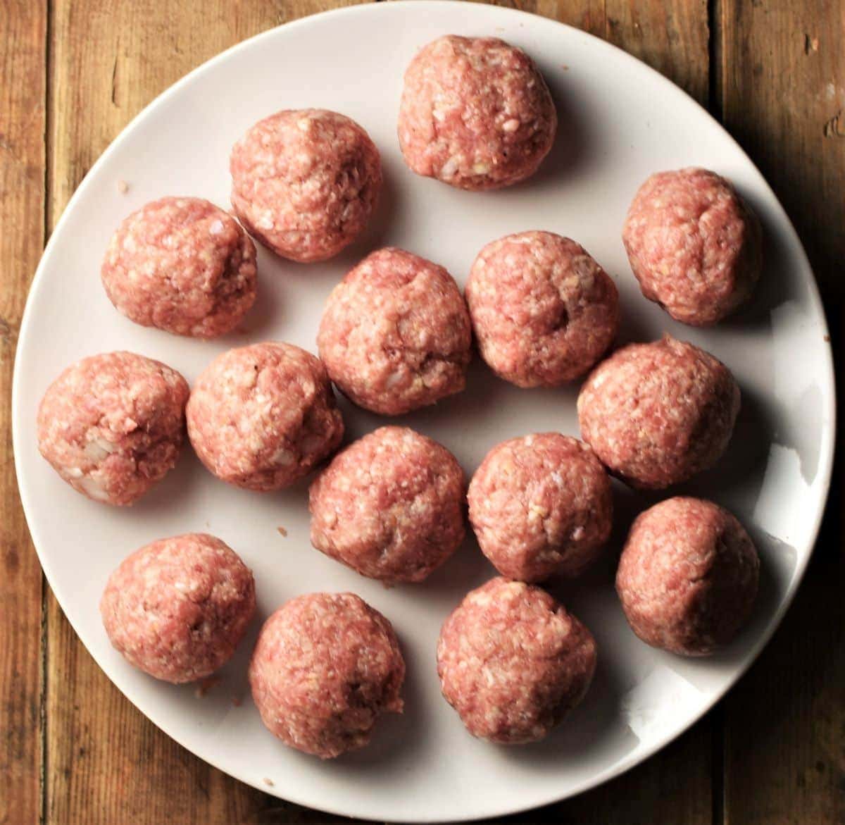 Raw meatballs on top of white plate.