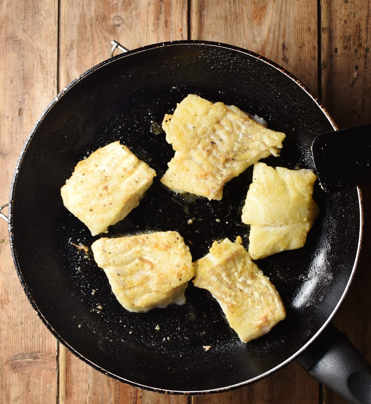 Fried fish fillets in skillet.