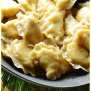 Close-up view of Polish potato and cheese pierogi in black bowl.