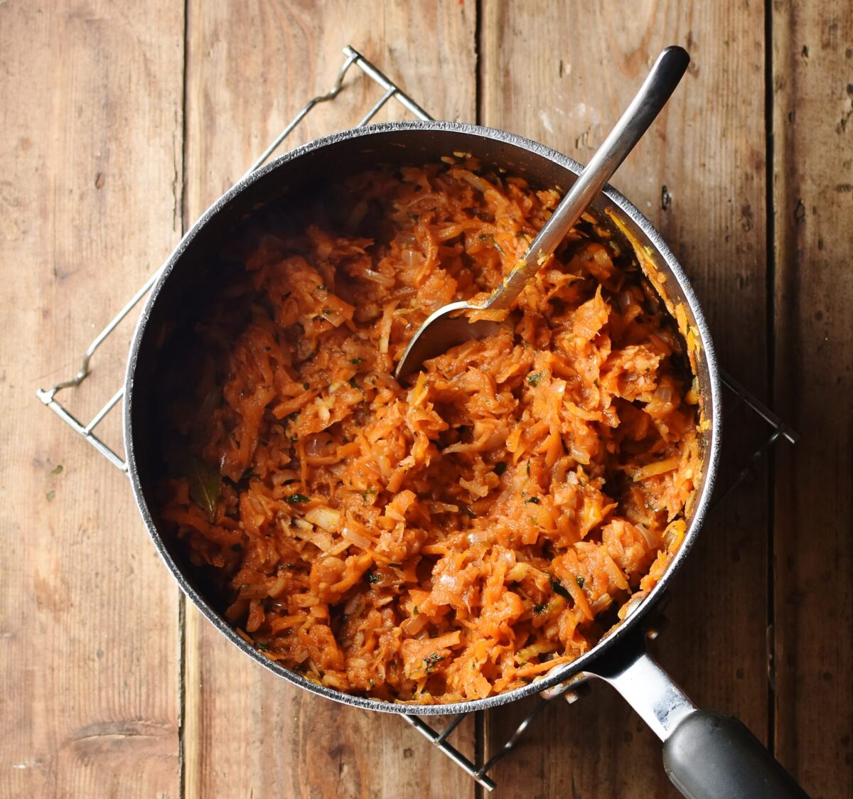 Grated stewed vegetables in large pot with spoon.