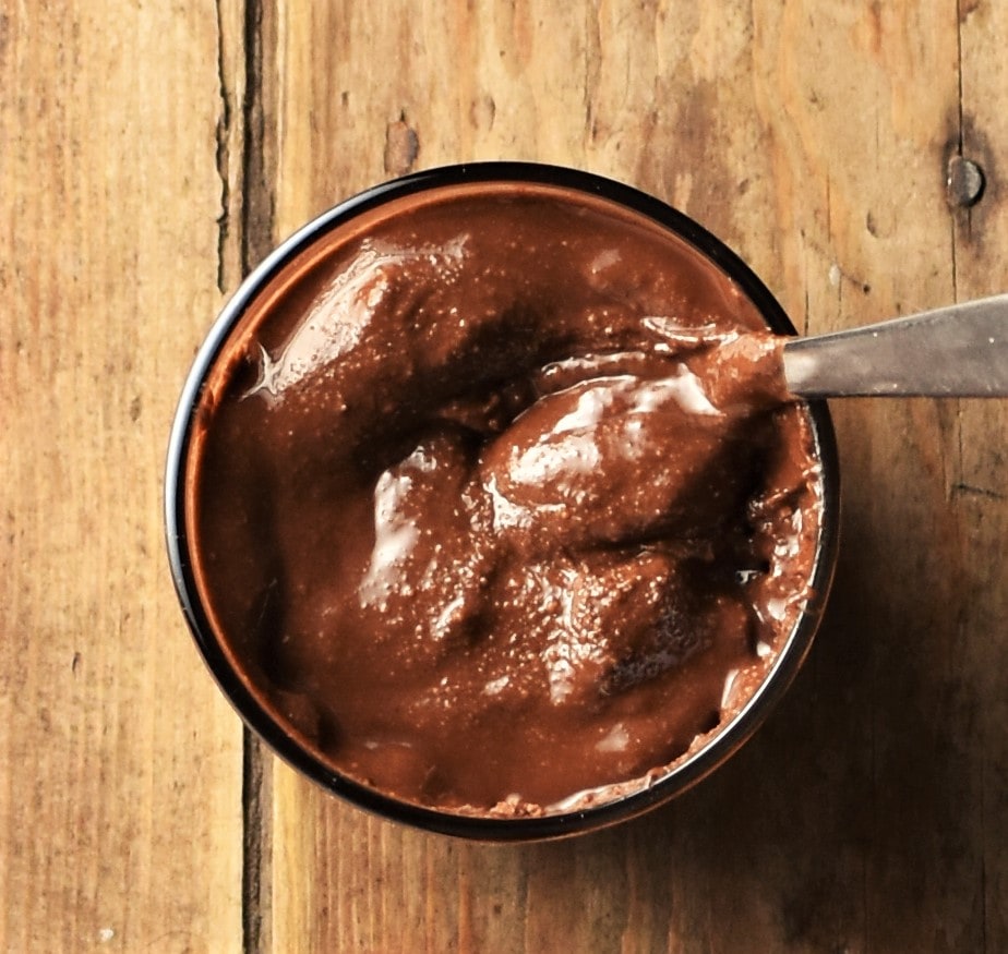 Top down view of hazelnut chocolate butter in cup with knife.