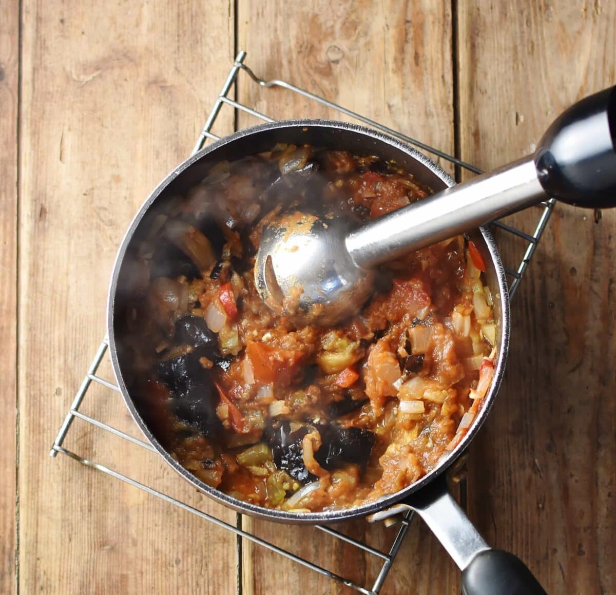 Thick tomato sauce with eggplant chunks and end of stick blender in large pot.