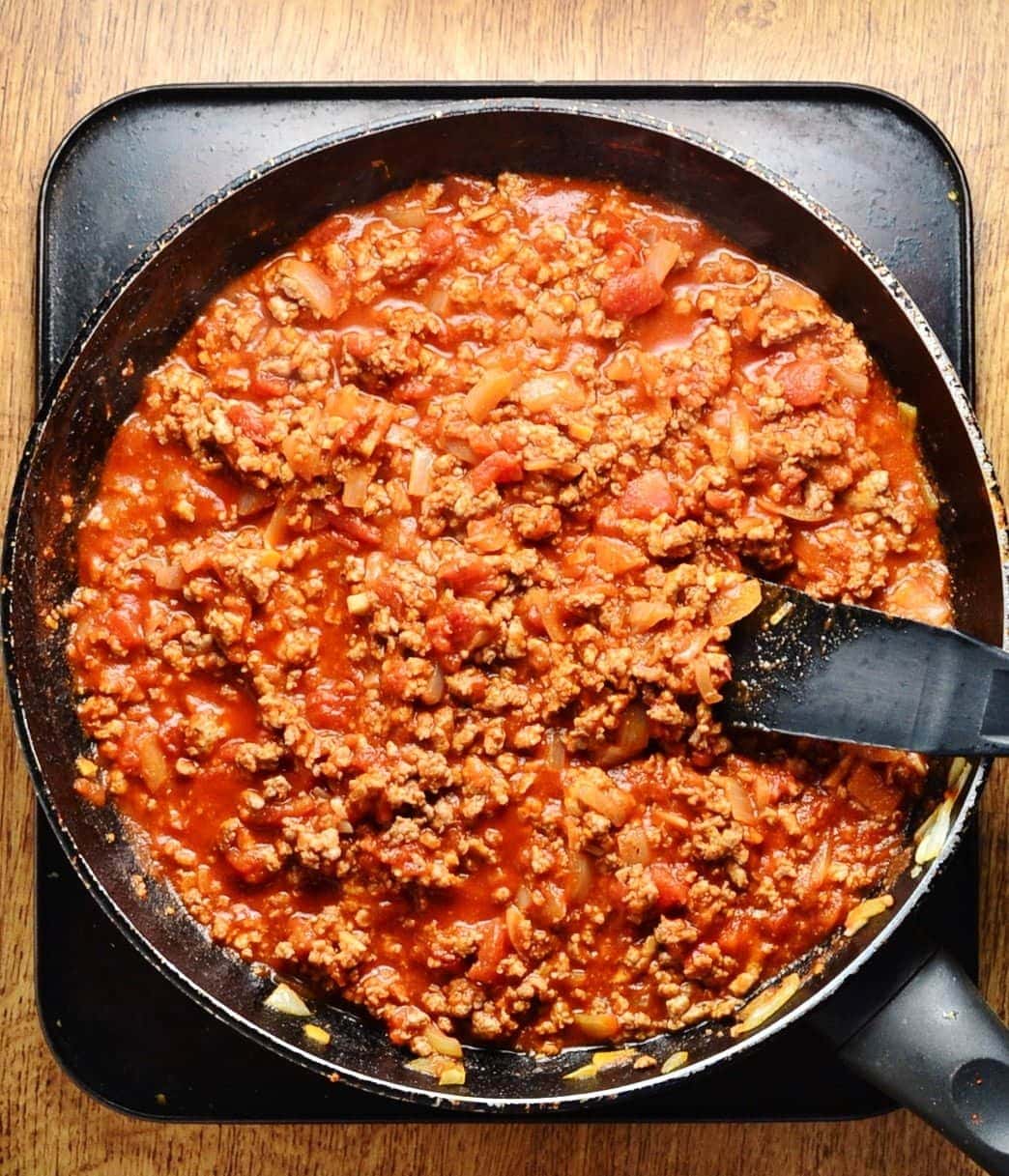 Turkey tomato sauce in pan with black spatula on oven tray.