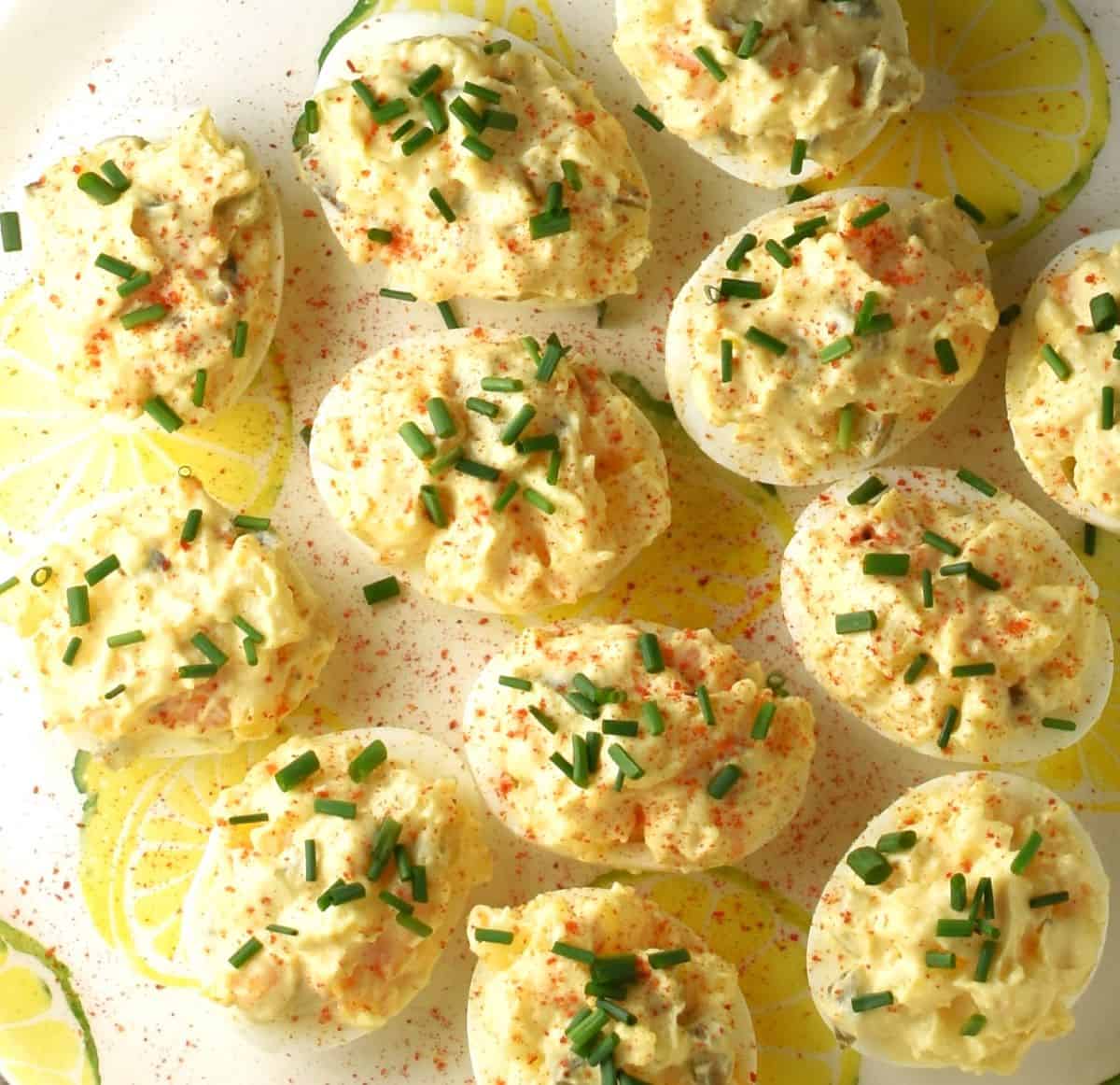 Deviled eggs filled with potato salad on top of white plate.