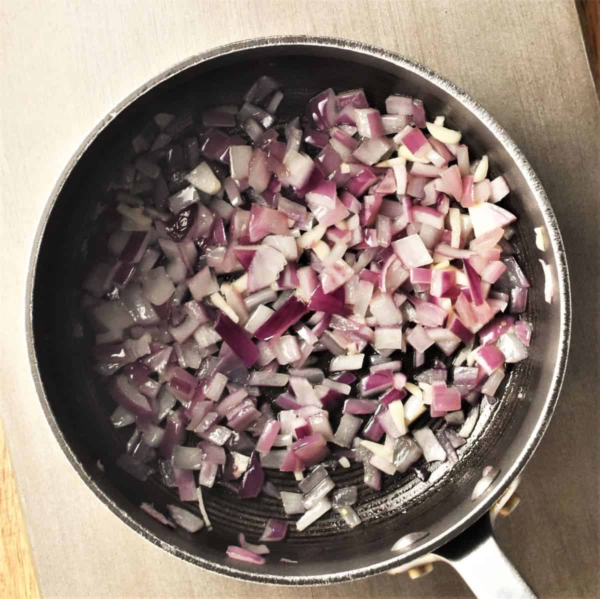 Frying chopped red onions for soup in pot.