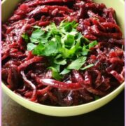 Braised red cabbage in yellow bowl with spoon and clementine in background.
