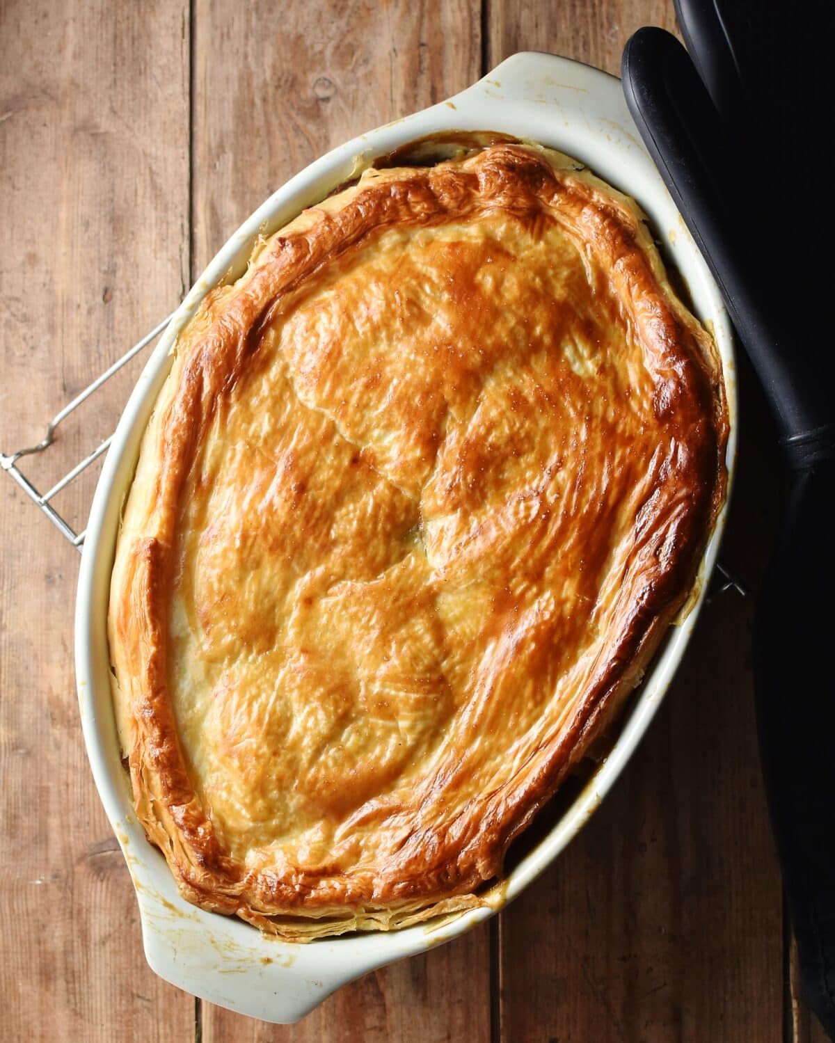 Pie with golden brown pastry on top in oval dish. 