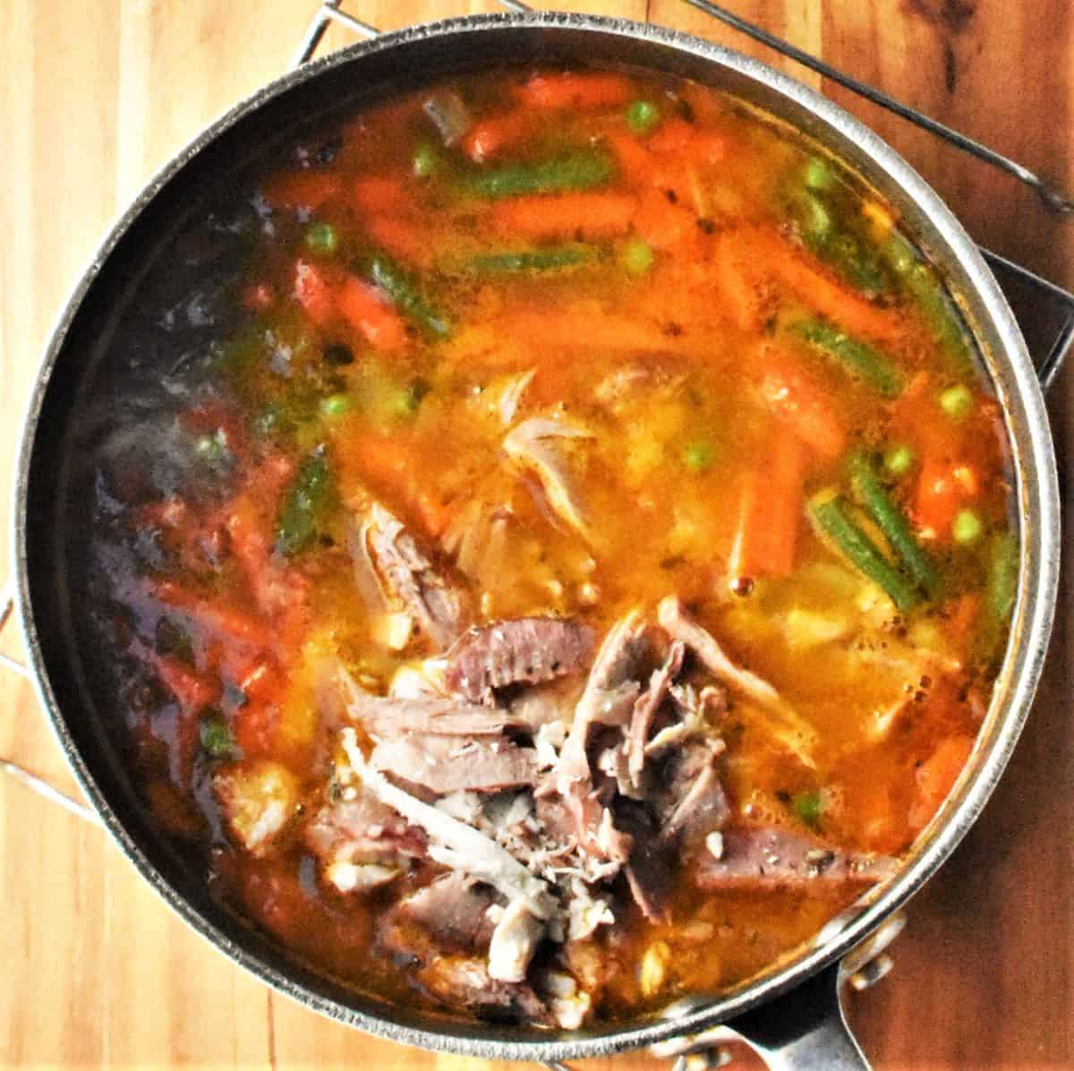 Soup with leftover turkey and vegetables in pot.