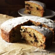 Side view of marzipan cake slice with cake in background on top of paper.