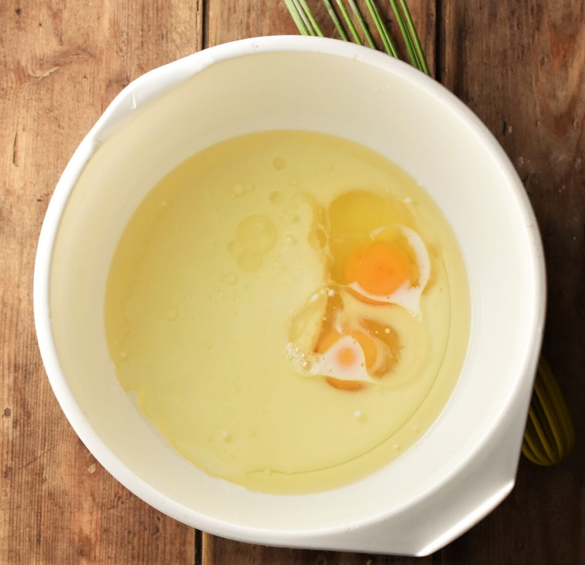 Milk, oil and 2 eggs in large white bowl.