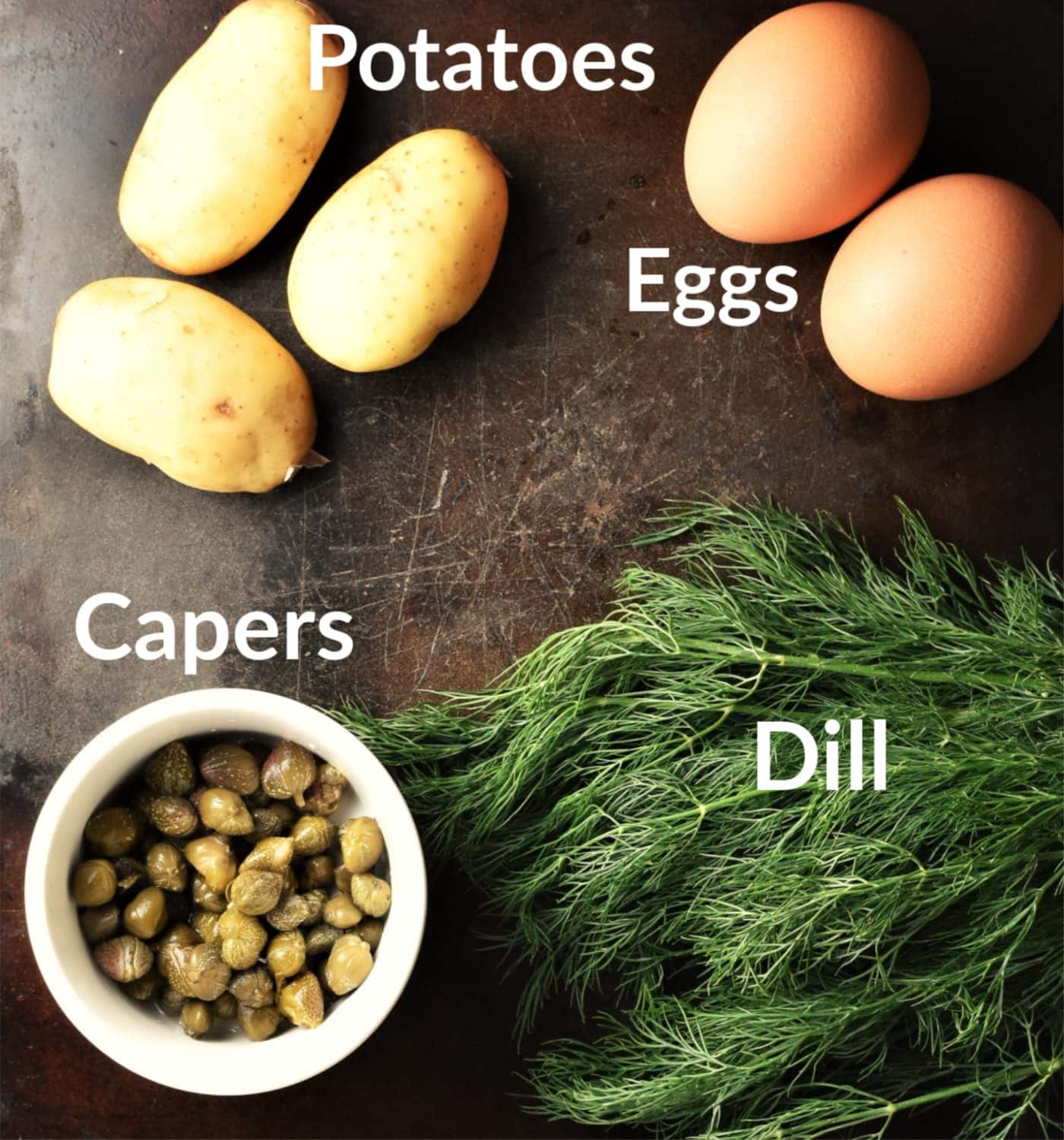 Potato dill salad ingredients on top of black surface.