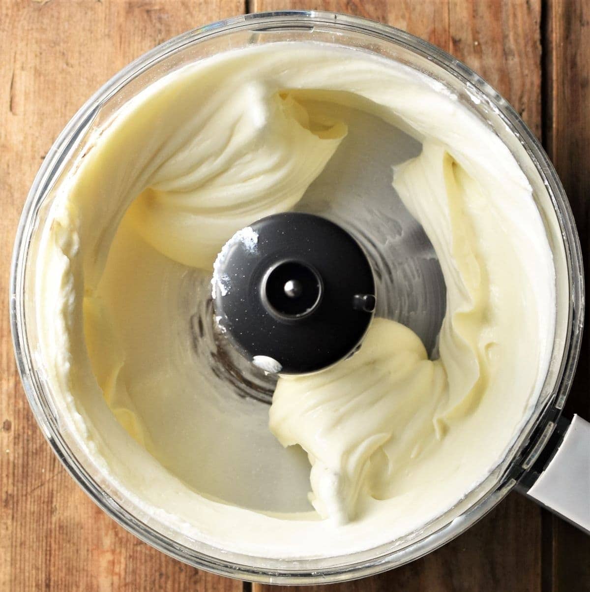 Creamy cheesecake filling in food processor bowl.