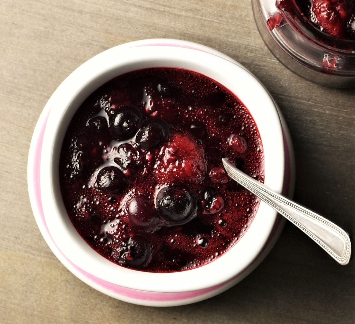 Top down view of fruit sauce in white bowl with spoon.