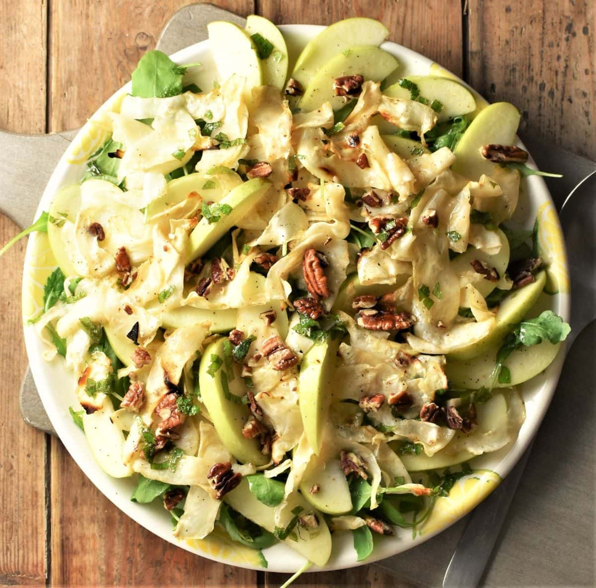 Top down view of roasted celery root salad with apple and pecans.