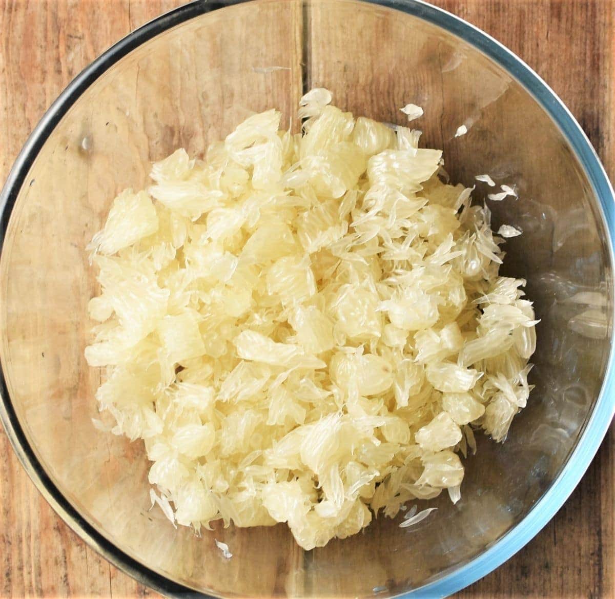Crumbled pomelo pulp in mixing bowl.