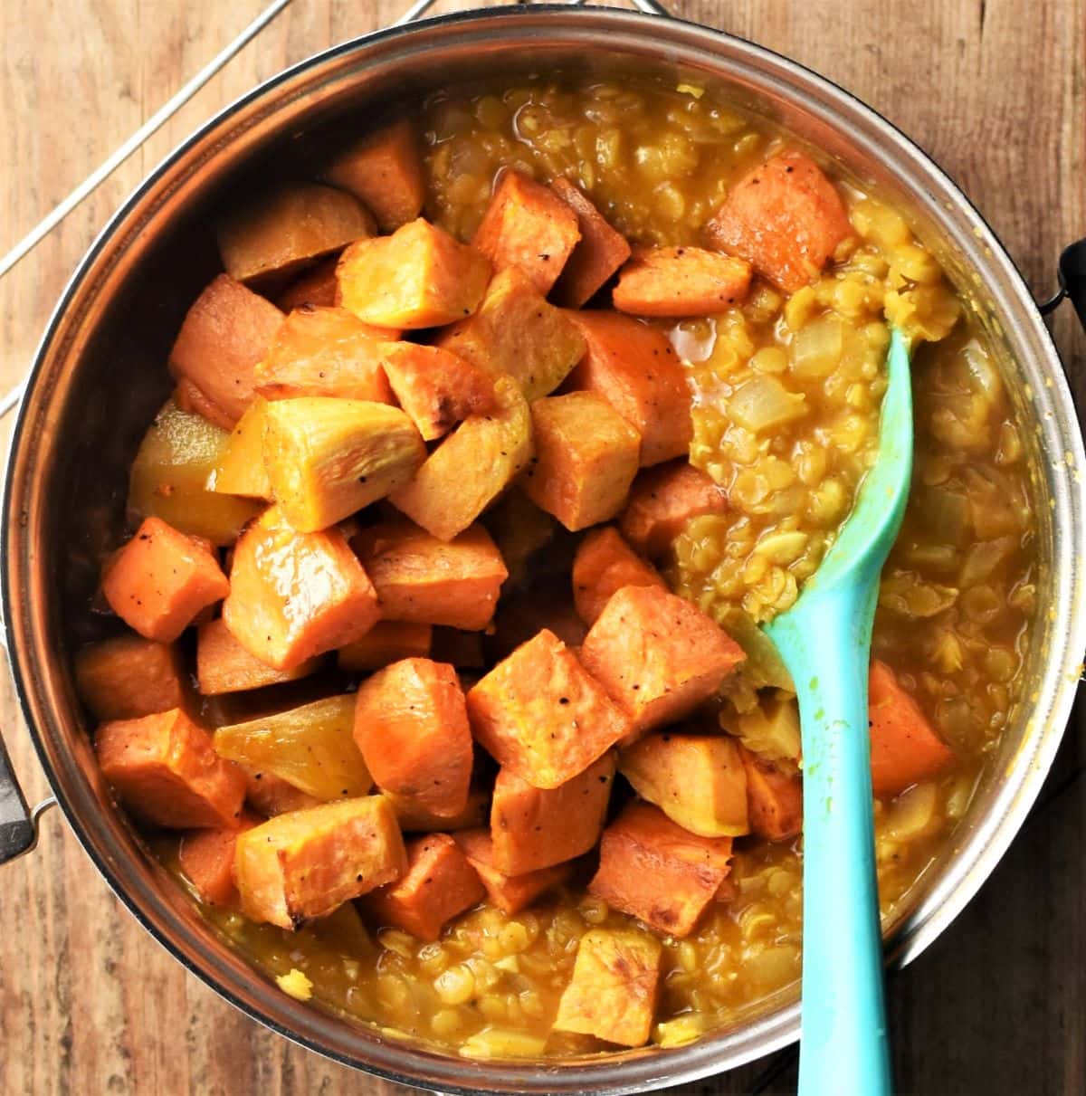 Cubed roasted sweet potato being stirred into dahl.