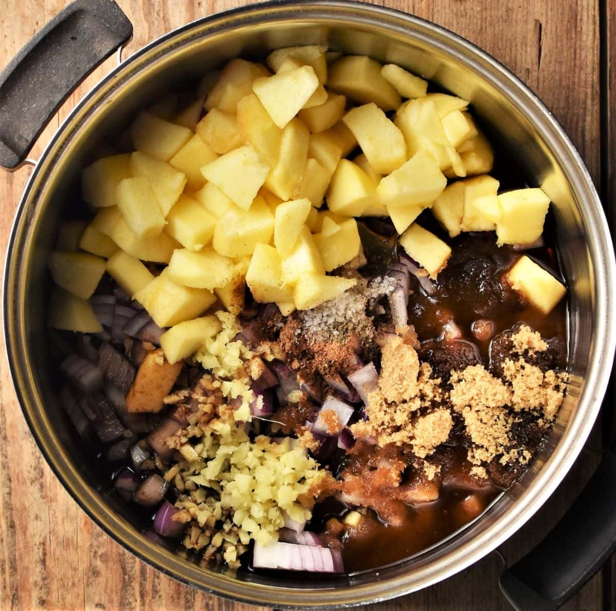 Chopped apple, onion and spices in pot.