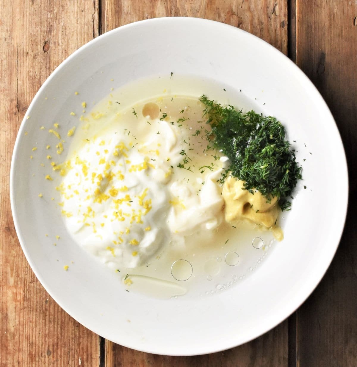 Combining dill lemon dressing ingredients in bowl.