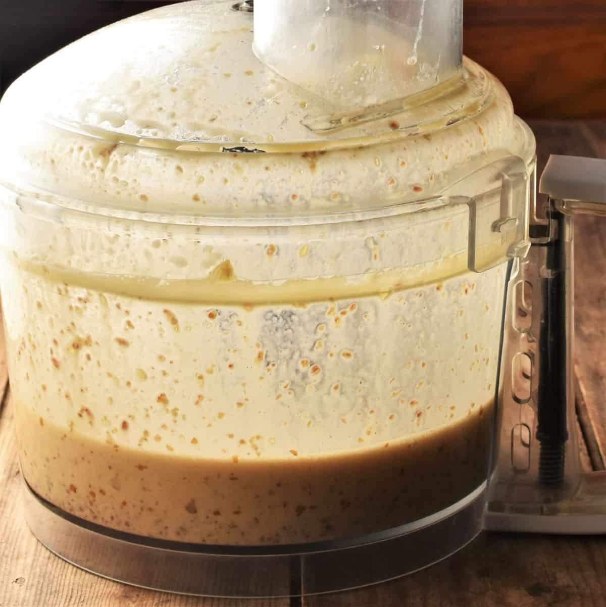 Side view of food processor bowl with  wet mixture for muffins.
