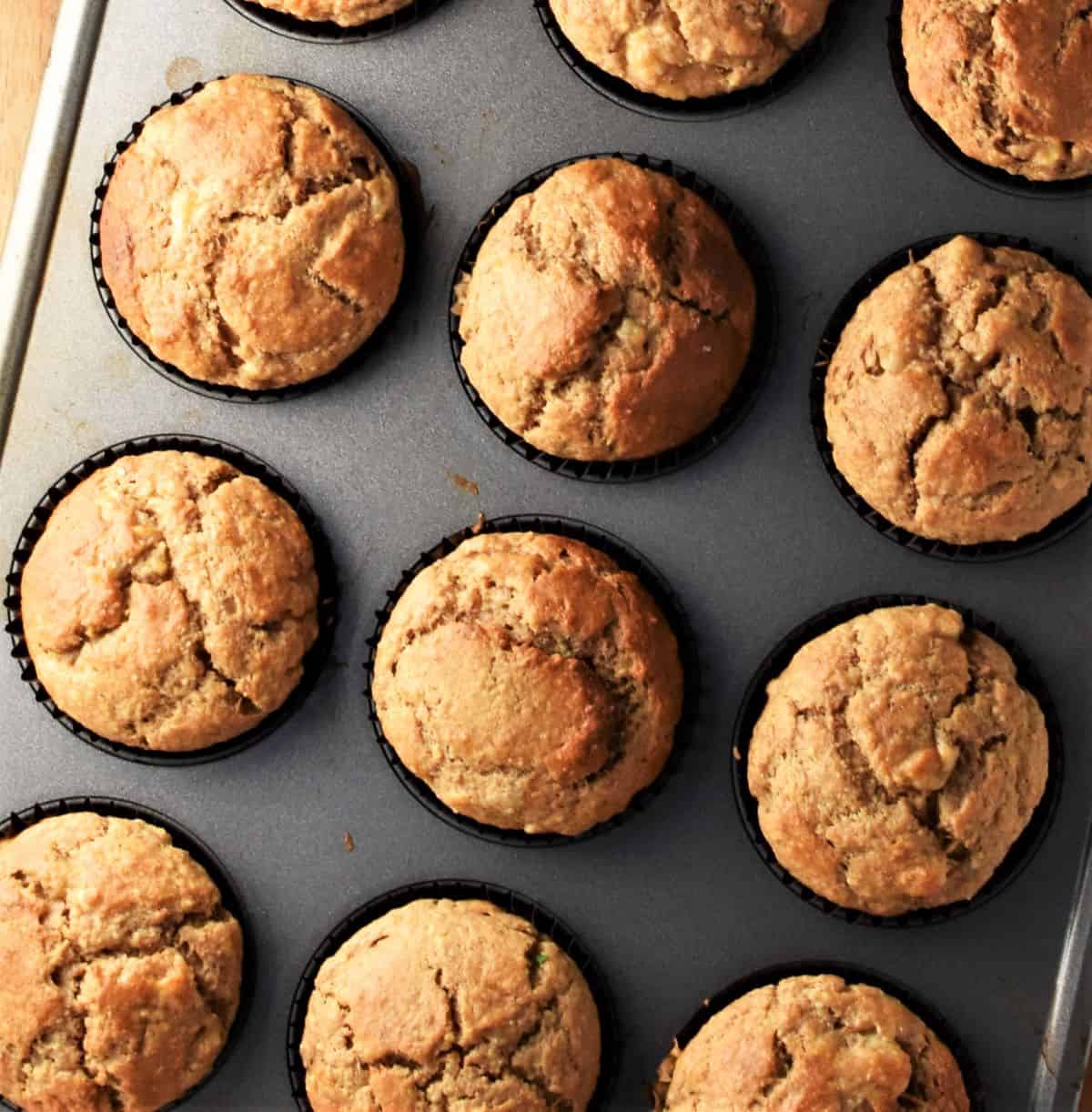 Banana and peanut butter muffins in paper cases inside muffin pan.