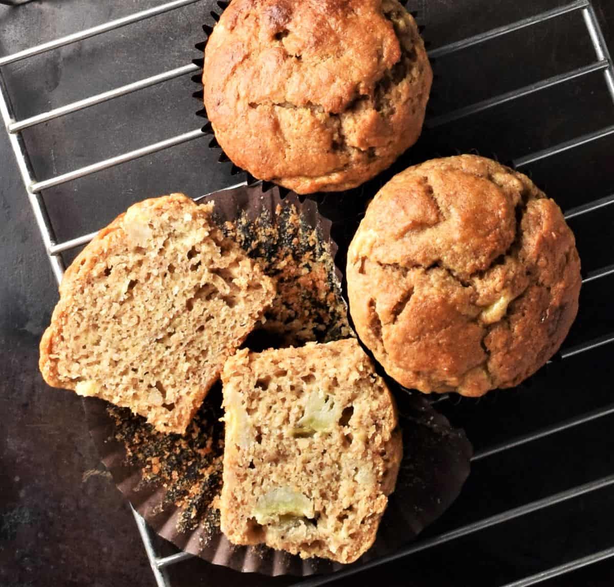 Banana peanut butter muffins, halved and whole, on top of rack.