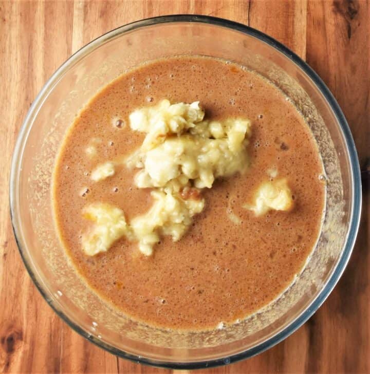 Wet muffin mixture with partly mashed banana in bowl.