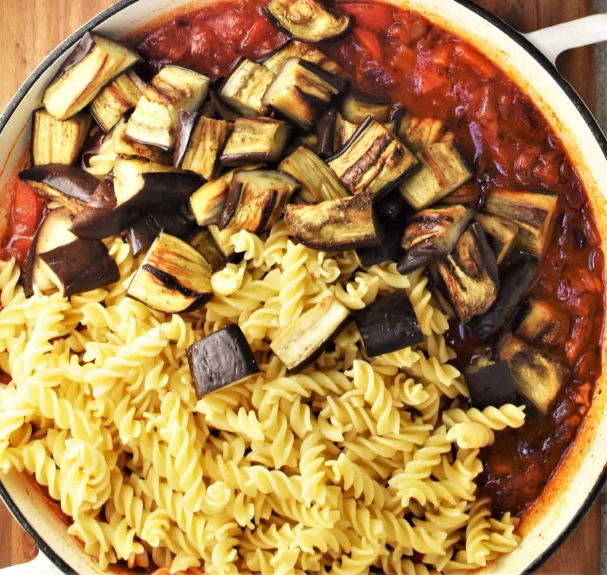 Assembling roasted eggplant and pasta bake in large shallow dish.
