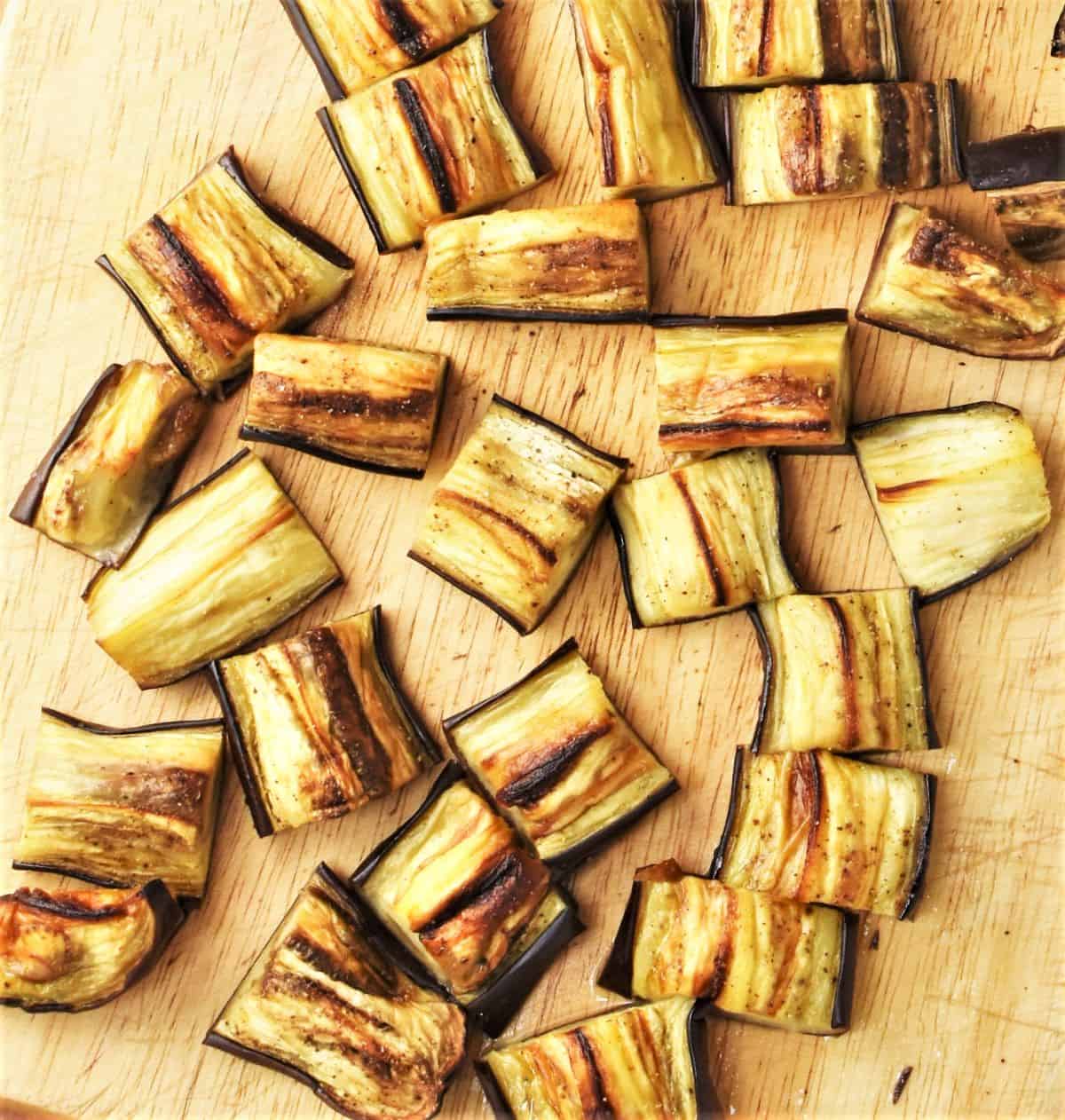 Chopped roasted eggplant on wooden board.