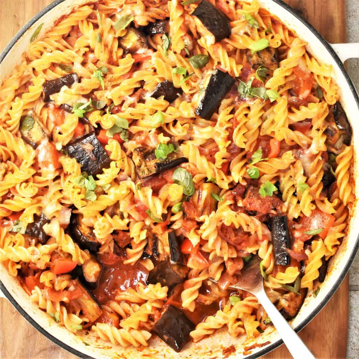 Top down view of eggplant pasta bake in large round dish with spoon.