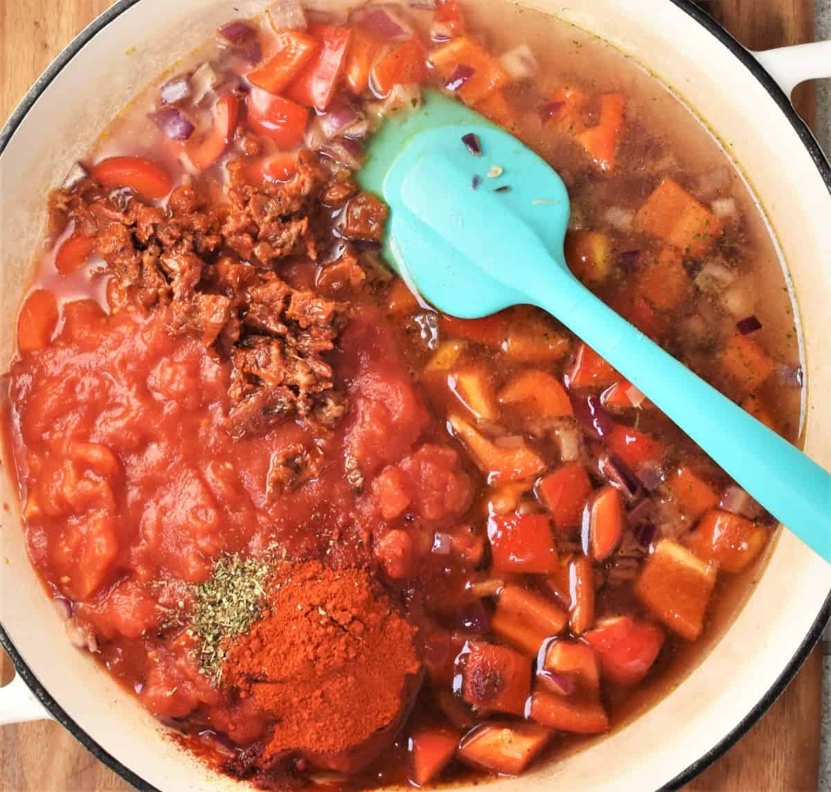 Making sauce in large dish with blue spoon for aubergine pasta bake.