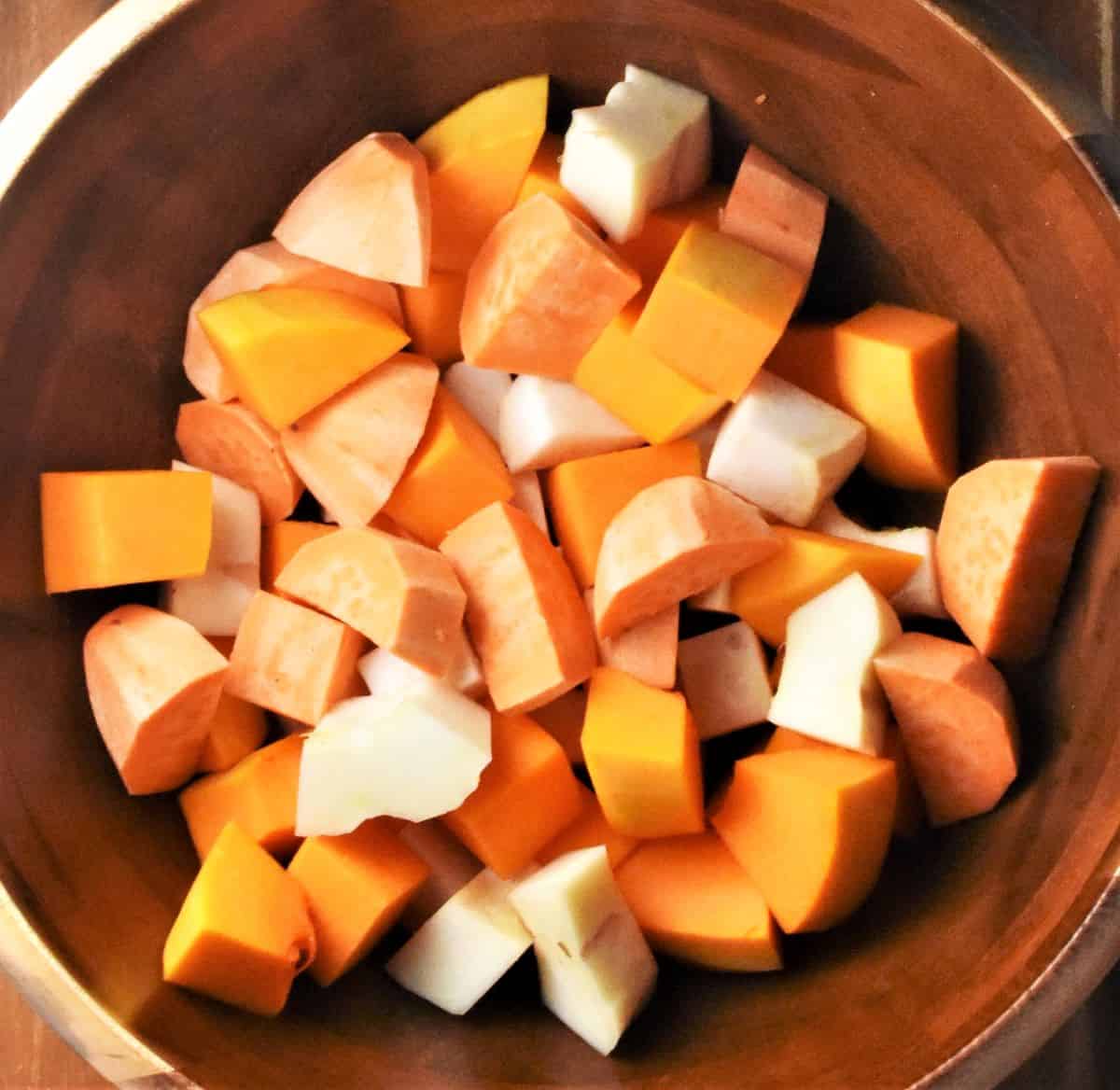Peeled cubed vegetables in large wooden bowl.
