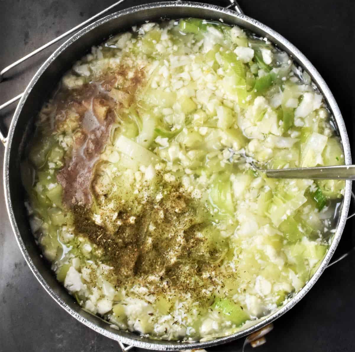 Chunky cauliflower leek soup with herbs and spoon.