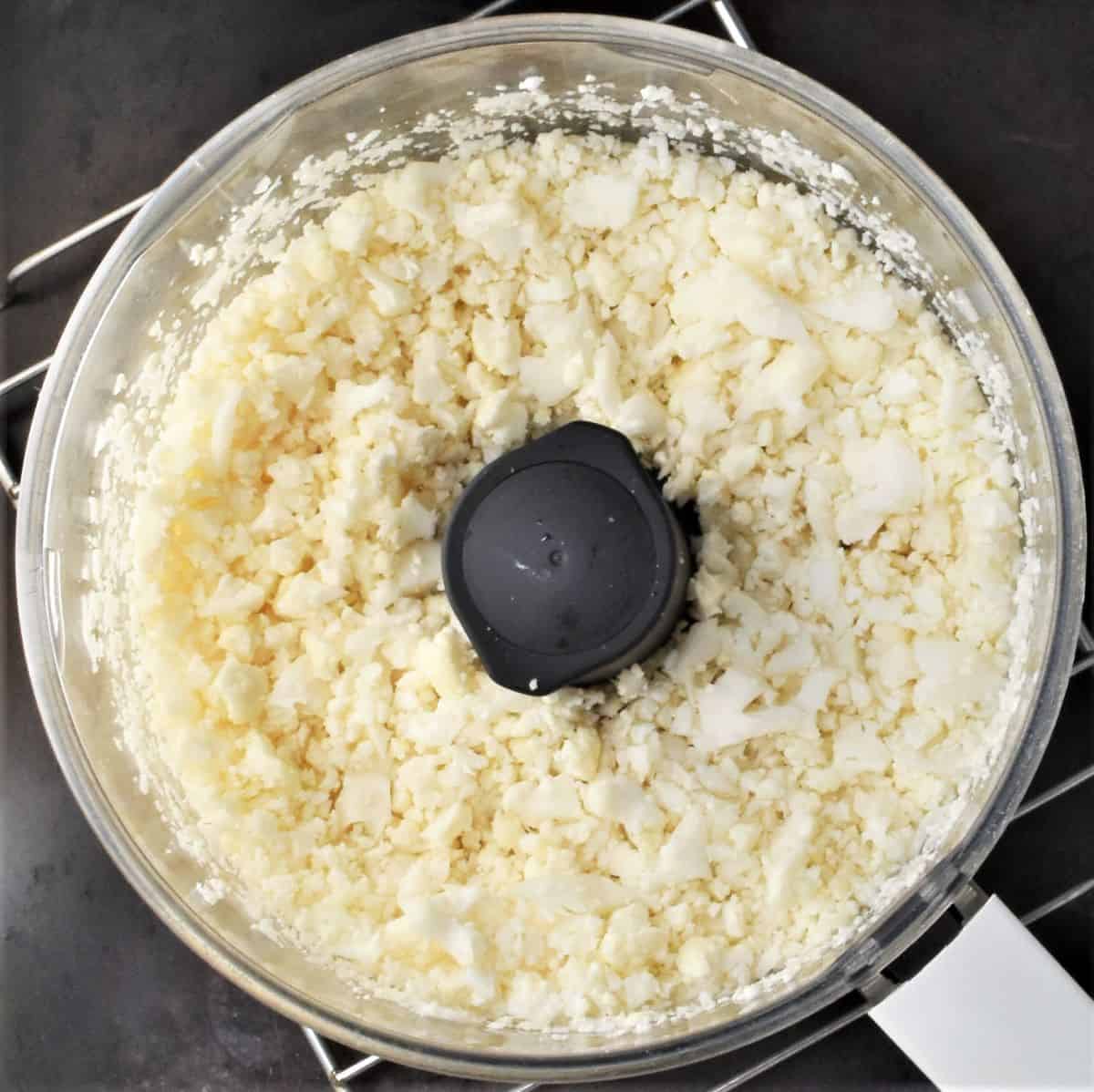 Chopped cauliflower in food processor bowl.