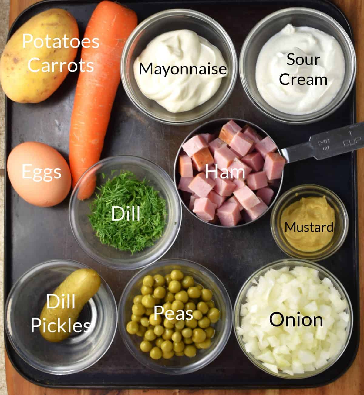 Top down view of ingredients for making Olivier potato salad in individual dishes.