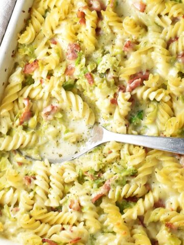 Top down view of brussels sprouts pasta bake with spoon in rectangular dish.