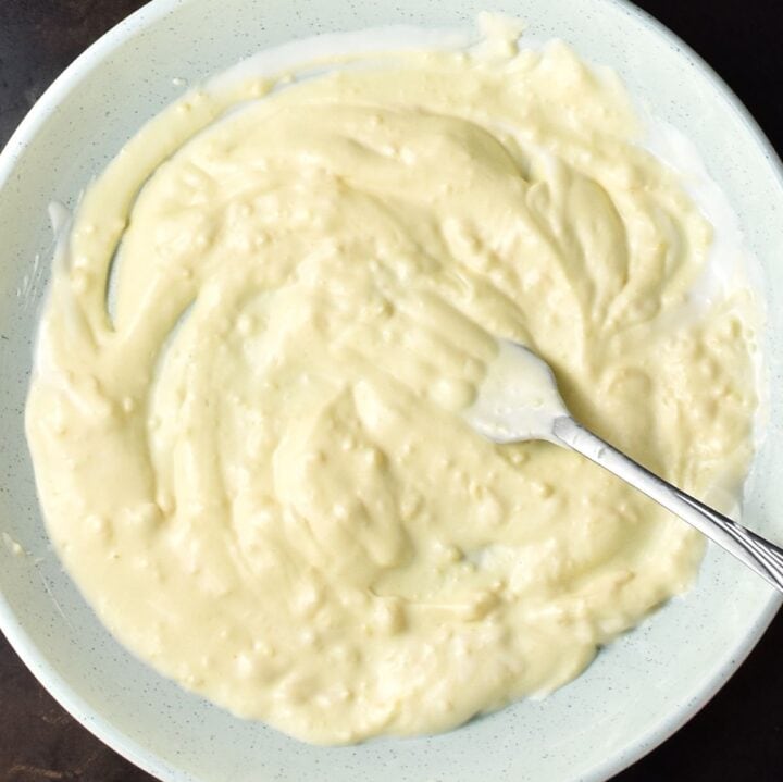 Top down view of creamy egg pickle salad dressing in large blue bowl with fork. 